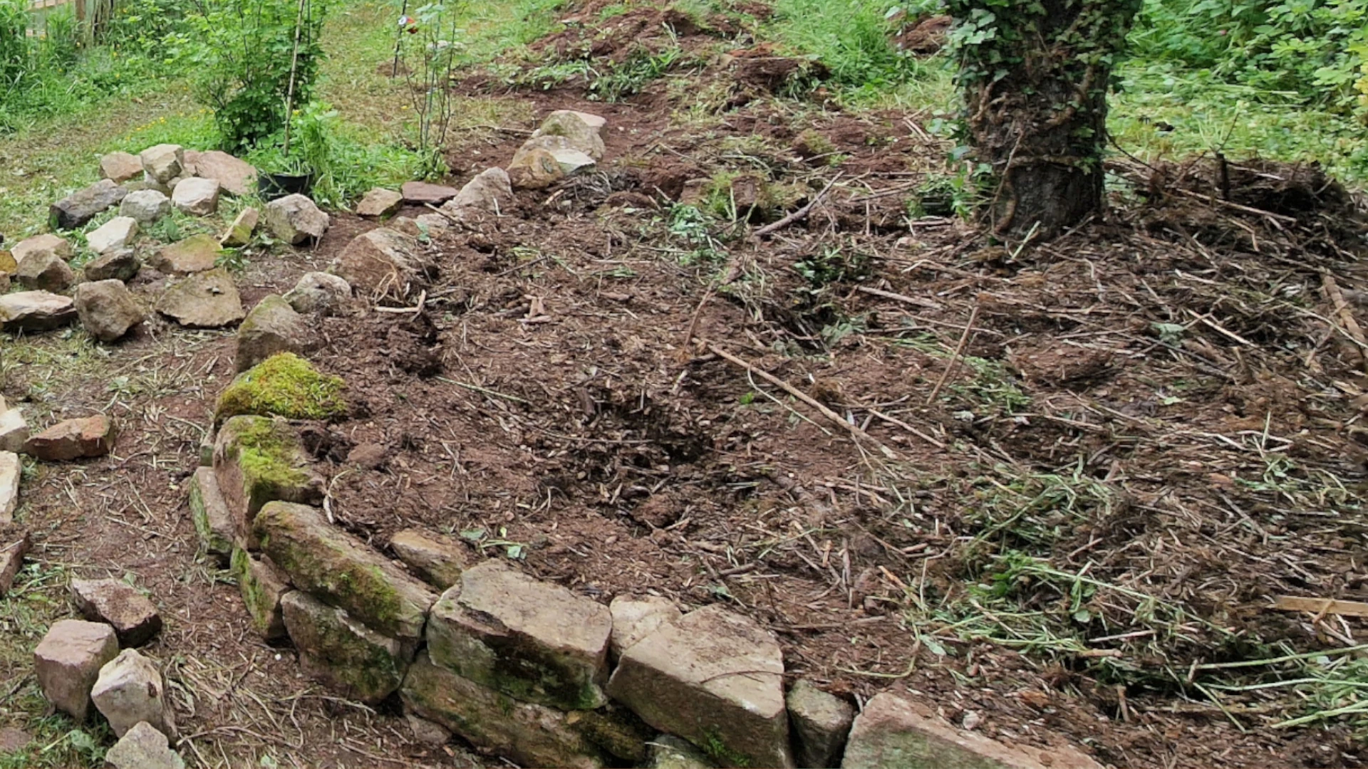 Waldbeet mit Natursteinmauer als Hangabfang
